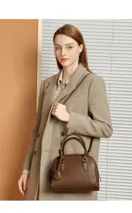 Borsa Boston in pelle marrone con finiture dorate e doppi manici su cappotto