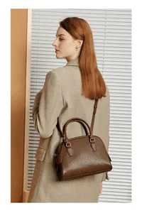 Borsa Boston in pelle martellata marrone indossata a spalla da una modella elegante