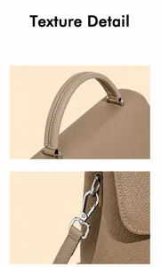 Detail of the curved leather handle and metal hook on a khaki pebbled leather bag