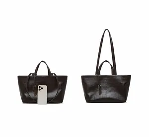 Borsa tote in pelle marrone scuro confrontata con iPhone 16 Pro e dettaglio tracolla