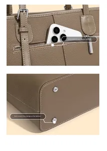 Detail view of the rear zipper pocket and metal protective bottom studs on the leather tote bag