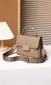 Close-up of pebble leather texture and woven shoulder strap on a taupe shell bag