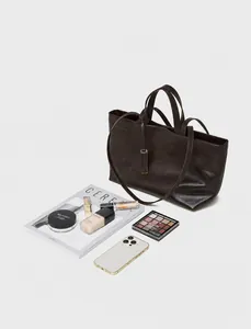Vista dettagliata del capiente interno della borsa tote in pelle marrone con oggetti
