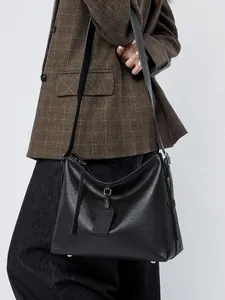 Large vintage black cowhide leather tote bag with shoulder strap worn by a female model