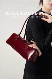 Dettaglio della borsa baguette in pelle bordeaux con doppie tracolle e zip argentata