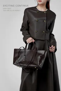 Dettaglio della borsa tote in pelle marrone scuro con borchie dorate sul fondo