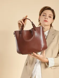 Borsa tote pendolare in vera pelle marrone scuro con manico regolabile mostrata dal modello