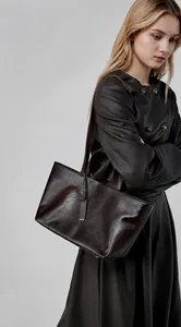 Dettaglio di una borsa tote grande in pelle marrone scuro con manici lunghi su modella