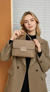 Model wearing a khaki lychee leather handbag with a wool coat in a modern studio setting
