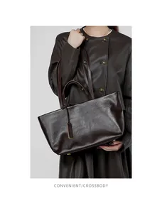 Dettaglio borsa tote grande in pelle marrone scuro con doppi manici e borchie dorate di base
