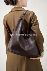 Bolso tote grande de cuero marrón oscuro llevado por una modelo con estilo minimalista