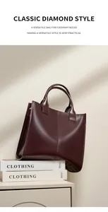 Dettaglio di una borsa tote in pelle bordeaux con manici cilindrici e finitura lucida