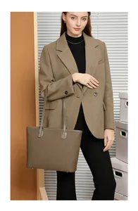 Detail of dark brown lychee grain leather tote bag with metallic buckle on a shoulder strap
