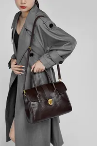 Borsa a cartella in pelle marrone scuro indossata da modella con trench grigio