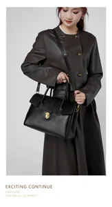 Dettaglio della borsa tote in pelle nera con chiusura a scudo dorata e trama pregiata