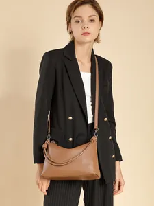 Minimalistische Damen Hobo-Tasche aus lohfarbenem Leder getragen von einem Model