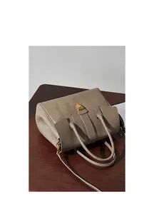 Detail of beige leather tote bag with gold metal twist lock and detachable strap