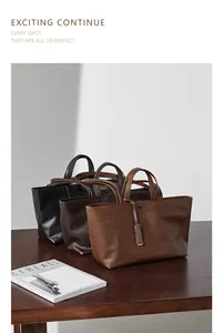 Tre borse tote in pelle nera, marrone scuro e marrone chiaro su una scrivania
