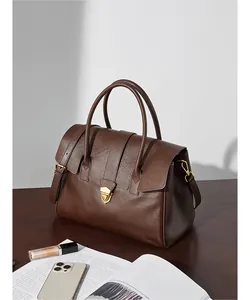 Dettaglio borsa tote vintage in pelle marrone scuro con finiture dorate su tavolo