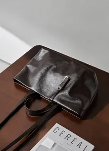 Dettaglio ravvicinato della borsa tote in pelle marrone scuro con texture lucida