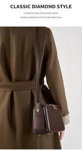 Brown leather crossbody bag detail on model wearing a caramel wool coat