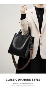 Dettaglio della borsa tote in pelle nera con tracolla in tessuto e doppi manici