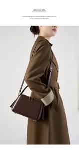 Detailed view of deep coffee leather bag with dual zippers worn over a classic trench coat