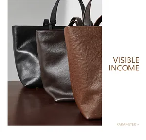 Borse tote minimaliste in pelle nera, caffè scuro e marrone su un tavolo di legno