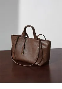 Vista dettagliata della borsa tote in pelle marrone e manici su tavolo di legno