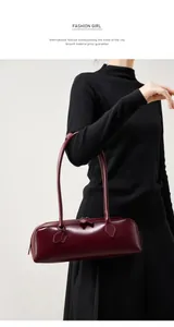 Dettaglio della borsa baguette in pelle bordeaux con focus su texture e manici