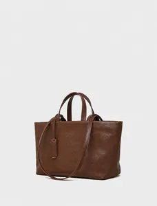 Dettaglio della borsa tote grande in pelle marrone scuro con grana fine e ciondolo