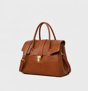 Detail of golden brown leather tote bag with metallic buckle and adjustable shoulder strap