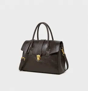 Detail of dark brown leather tote bag with gold buckle and adjustable shoulder strap
