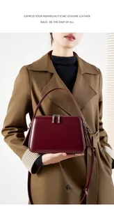 Detail of burgundy genuine leather handbag with silver zippers and adjustable strap