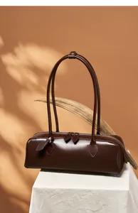 Dettaglio macro della borsa in pelle lucida marrone scuro con doppia cerniera e tracolle