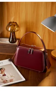 Detail view of burgundy leather square bag with double zippers and silver hardware