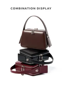 Detailed view of square leather handbags in brown, black, and burgundy with double zippers