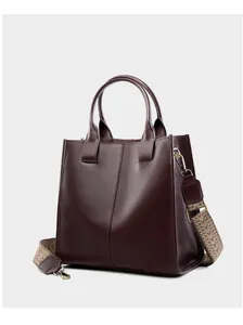 Dettaglio borsa tote in pelle bordeaux con fibbie in bronzo vintage e tracolla etnica