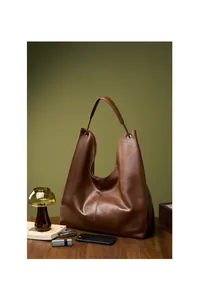 Detalle del bolso tote de cuero marrón oscuro en un elegante entorno de oficina
