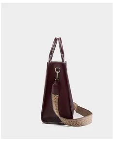 Dettaglio della borsa tote in pelle bordeaux con trama vintage e tracolla con motivi