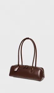 Dettaglio borsa baguette in pelle marrone scuro con cerniere metalliche e tracolla lunga