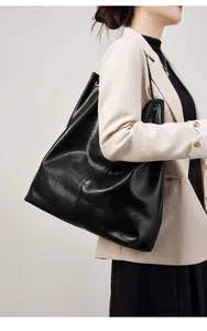 Detalle de un bolso tote grande de cuero negro con cordones laterales en modelo