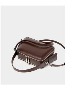 Detailed top-down view of a dark brown leather crossbody bag with silver double zippers