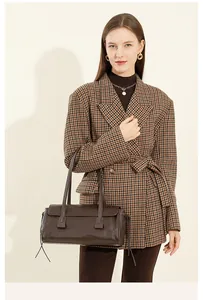 Detail view of a vintage dark brown leather handbag styled with a houndstooth blazer