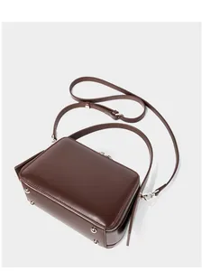 Detail of dark brown leather handbag with silver bottom studs and adjustable strap