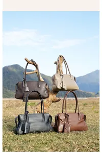 Detalle de bolsos tote de cuero en cuatro colores colgados de una rama de madera al aire