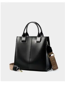 Dettaglio della borsa tote in pelle nera con tracolla in tessuto a motivi etnici