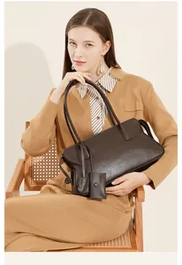 Detalle de bolso tote de cuero marrón oscuro con pequeño colgante y textura natural