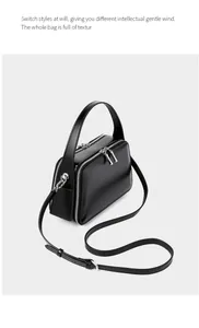 Detail of black leather handbag featuring dual zipper compartments and silver hardware