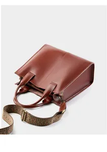 Dettaglio borsa tote in pelle marrone con tracolla larga a motivo etnico decorativo